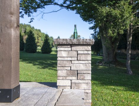 Detail of hardscaped patio pole with green torch bottle