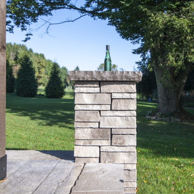 Detail of hardscaped patio pole with green torch bottle