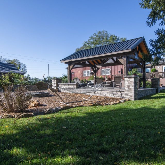 Wide angle photo from back of property showcasing pavilion, hammock, and hardscaped entertainment space