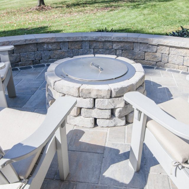 hardscaped outdoor fire pit with metal cover