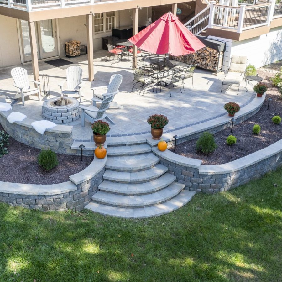 aerial drone shot of hardscaped patio, retaining walls, and steps to the backyard