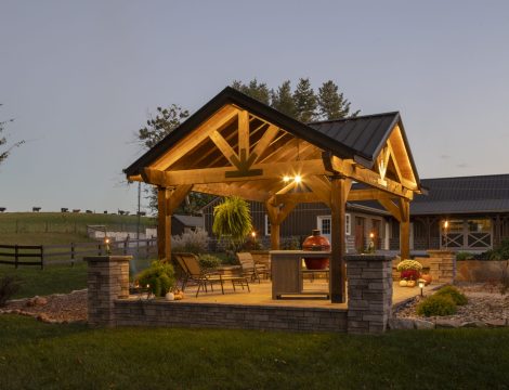 Pavilion illuminated at night with outdoor seating and kitchen underneath