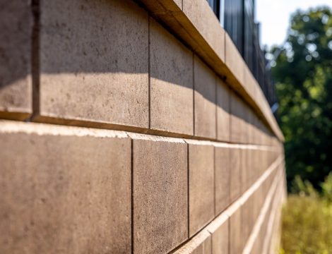 Close-up of tan concrete retaining wall blocks with smooth capstone edge