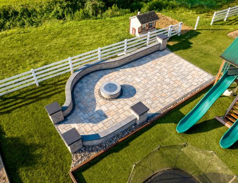 Aerial view of curved paver patio with stone seating wall and circular fire pit