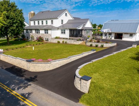 Curved concrete retaining wall and asphalt driveway surrounding residential property