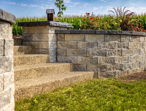 Concrete retaining wall with textured blocks and exposed aggregate steps leading to upper yard