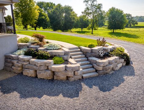 Natural stone retaining wall with built in steps and landscaped flower beds