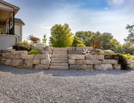 Tiered natural boulder retaining wall with central stone steps and landscaped plantings