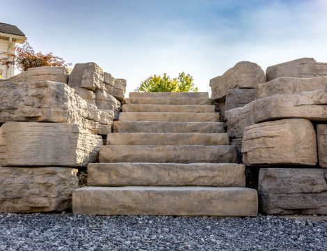 Front view of natural stone steps framed by large stacked boulder retaining walls